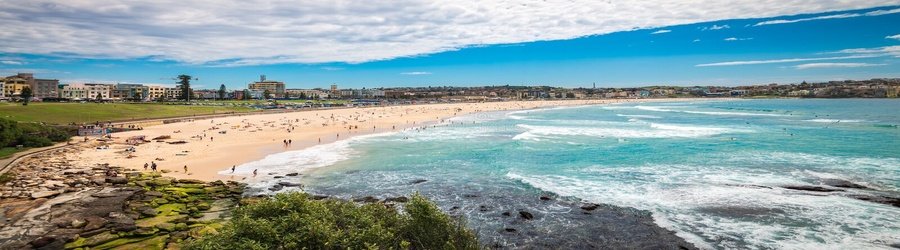 Bondi Beach with golden sand, turquoise waves, and people enjoying the surf and shoreline.