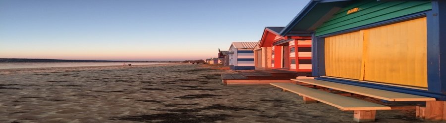 Colorful bathing boxes along Dromana Beach in Melbourne at sunset.