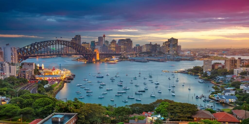 Beaches of Sydney, Sydney Harbour view with the iconic Harbour Bridge, city skyline, and boats at sunset.