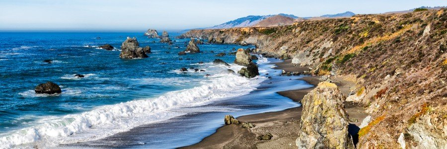 Rugged Sonoma County coastline with crashing waves, sea stacks, and a black sand beach along the Northern California coast