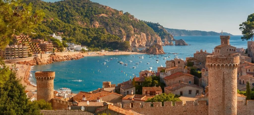 Best of Spain – coastal bay with medieval stone towers and boats on the Costa Brava.