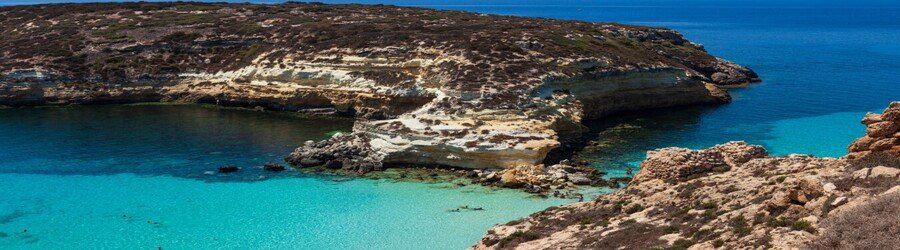 Spiaggia dei Conigli beach in Lampedusa with clear turquoise water and rocky shoreline