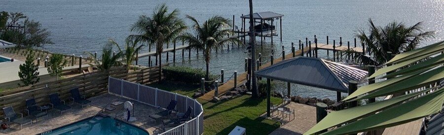 Waterfront view with pool, dock, and palm trees at Lost Inn Paradise near Cocoa Beach.