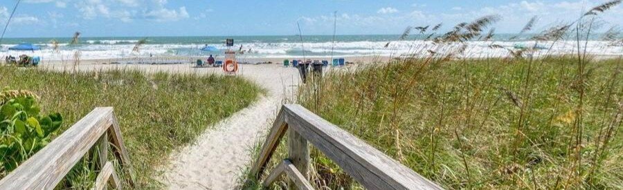 Boardwalk leading through coastal dunes to the beach at Penguins On The Beach Resort in Cocoa Beach.