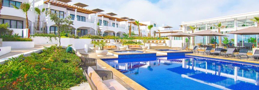 Modern pool area at Bellafer Collection Hotel in Rosarito Mexico with lounge seating, tropical landscaping, luxury suites, and bright coastal resort architecture.