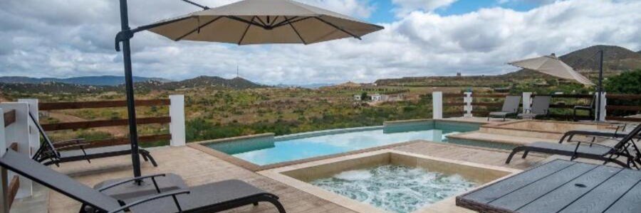 Modern hotel pool and hot tub area with sun loungers and umbrellas overlooking the San Felipe desert mountains.