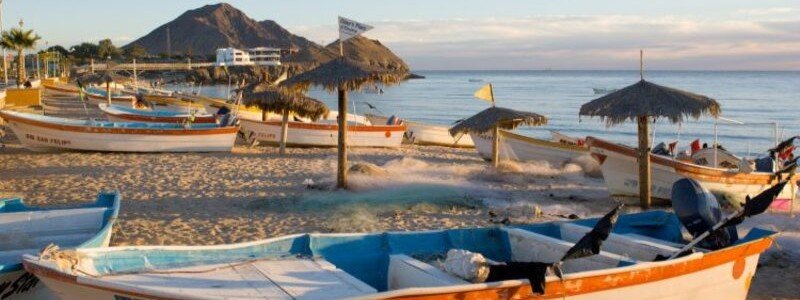 Traditional blue and white panga fishing boats resting on the sandy beach of San Felipe at low tide.