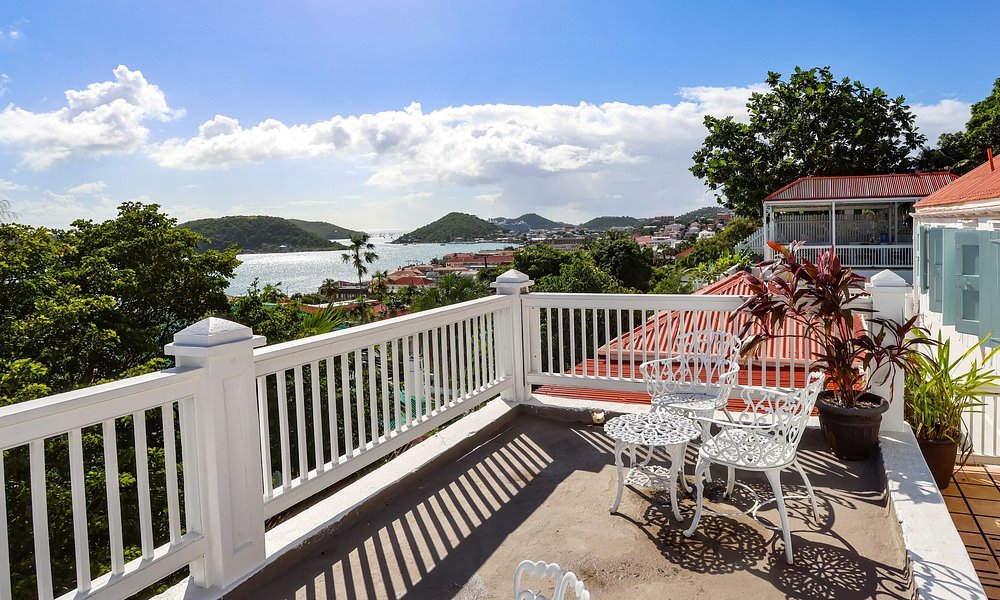 Outdoor terrace at At Home in The Tropics Inn in St thomas with white railing, seating, and harbor views