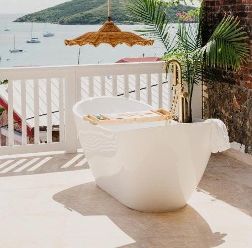 Outdoor soaking tub at The Pink Palm Hotel in St thomas with balcony view of ocean and hillside