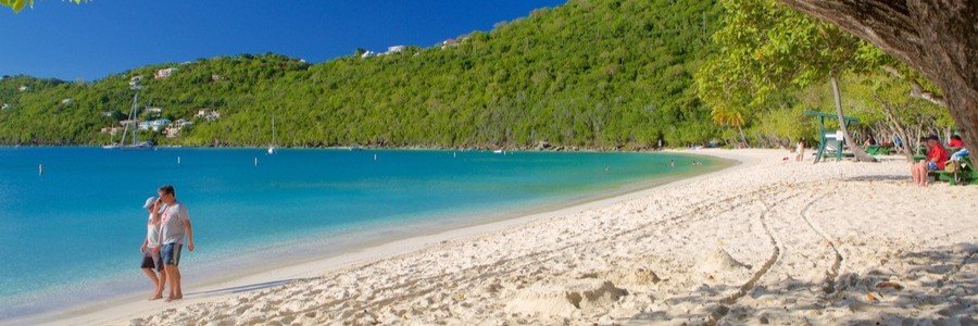 Magens Bay Beach in St thomas with white sand, calm turquoise water, and people walking along the shore