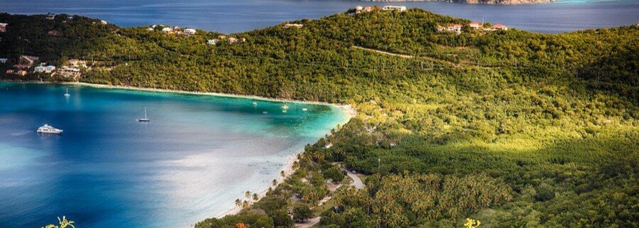 Aerial view of a turquoise bay in St thomas with lush green hills and boats anchored in calm water