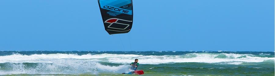 Kitesurfer gliding across choppy ocean waves with a bold blue kite.