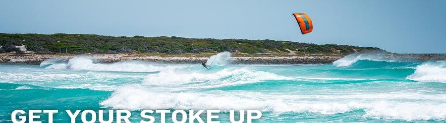Kitesurfer launching off a wave in dramatic turquoise surf.
