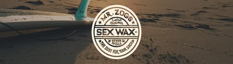 Mr. Zoggs Sex Wax logo with surfboard on the beach at sunset.