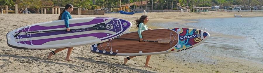 Best stand-up paddleboarding banner – paddlers carrying inflatable SUP boards along sandy beach