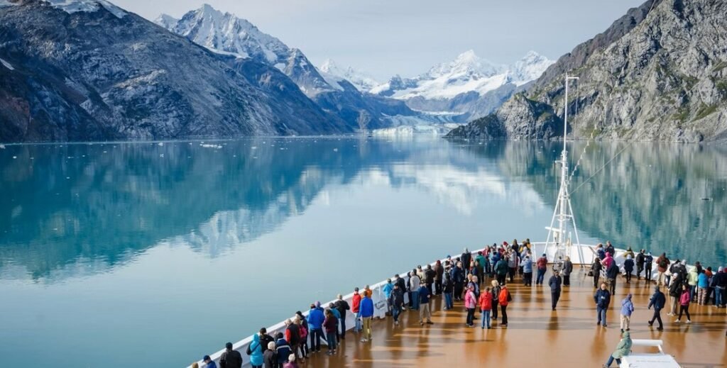 Passengers on Alaska cruise ship deck viewing glacier mountains and icy fjord scenery