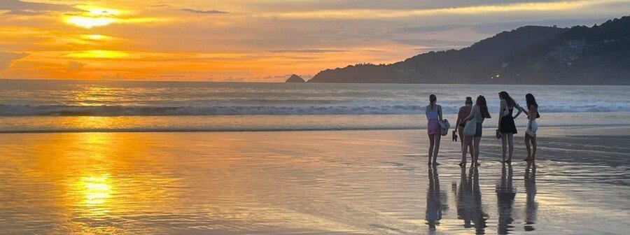 Phuket Thailand beach sunset with golden sky, shoreline reflections, and tropical coastal scenery