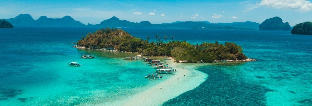 El Nido island hopping with boats on a sandbar and clear blue water