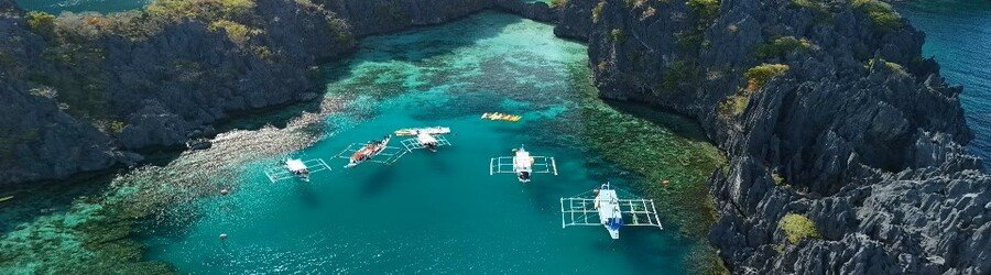 Island hopping in El Nido with boats in a calm blue lagoon