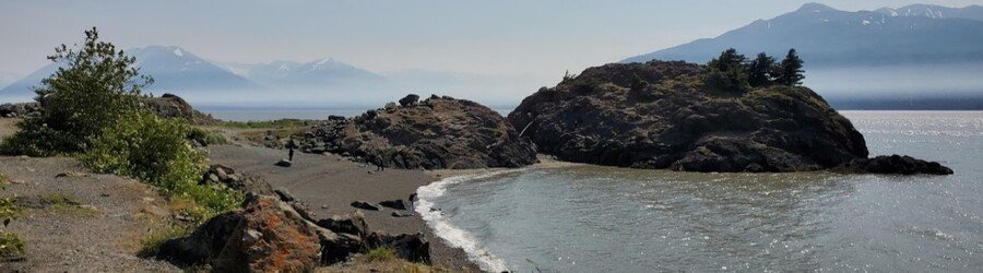Rocky coastline at Beluga Point near Anchorage with misty mountains across Turnagain Arm.