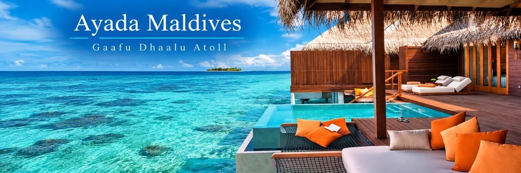 Luxury overwater villa featuring a private infinity pool, wooden sundeck, orange cushions, shaded loungers, and crystal-clear turquoise lagoon waters.