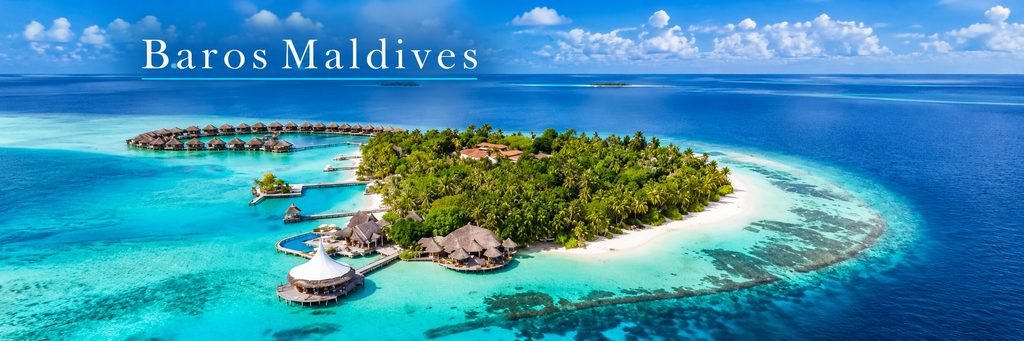 Aerial view of a lush private island resort surrounded by turquoise lagoons, white-sand beaches, coral reefs, and elegant overwater villas.