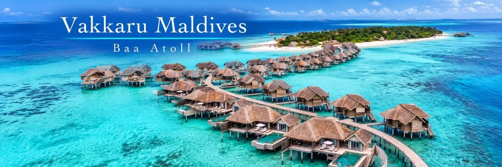 Aerial view of luxurious thatched-roof overwater villas connected by winding wooden walkways above a crystal-clear turquoise lagoon.