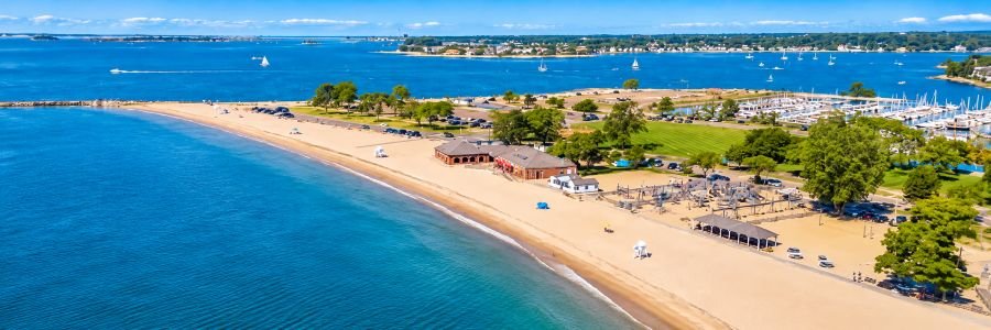 Aerial view of Compo Beach, one of the popular Westport Beaches in Connecticut, featuring sandy shores, blue water, and a marina along Long Island Sound.