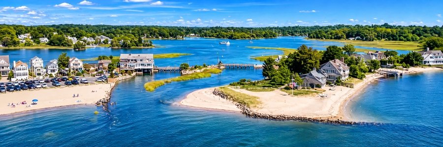 Aerial view inspired by Old Mill Beach, one of the Westport Beaches in Connecticut, featuring sandy shores, blue water, coastal homes, and Old Mill Pond.