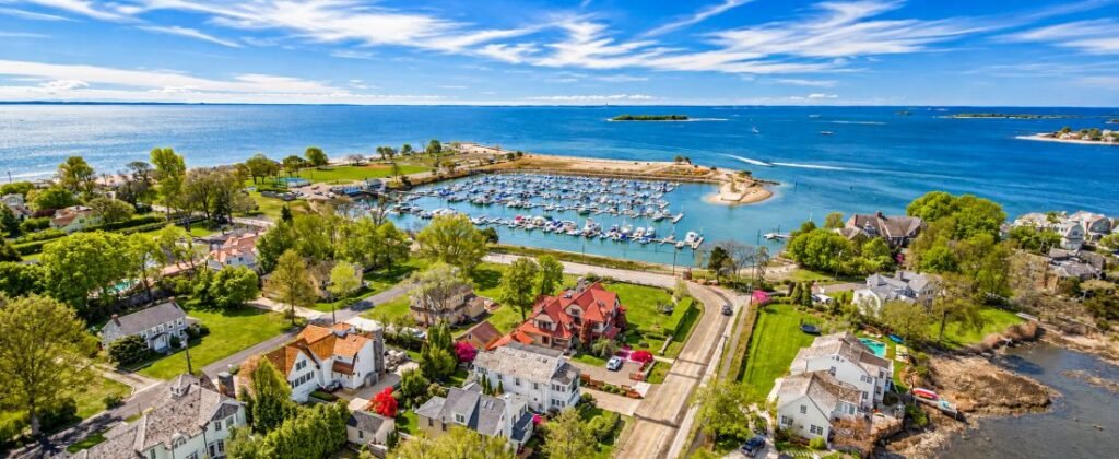 Aerial view of Westport Beaches in Connecticut, featuring a marina, coastal homes, sandy shoreline, and blue waters of Long Island Sound.
