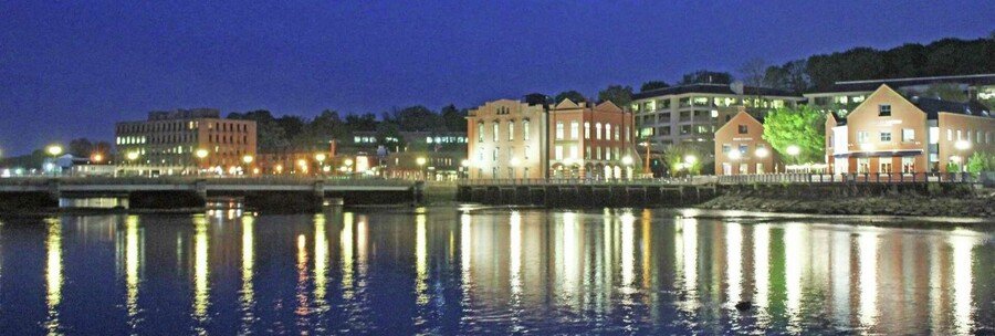 Westport Connecticut riverfront at night with illuminated buildings reflecting on the water