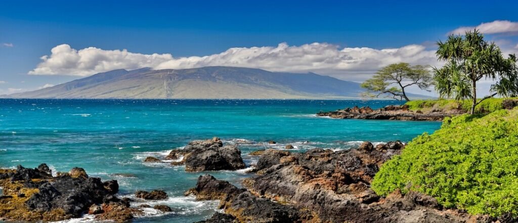 Rocky shoreline with turquoise ocean and views of mountains and coastline of Maui Hawaii