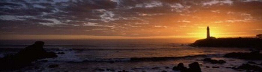 Silhouette of a lighthouse at sunset along the rocky San Mateo coast.