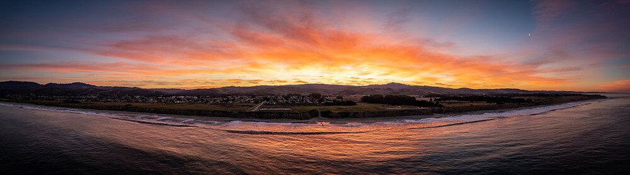 Wide coastal view of San Mateo County at sunset with rolling hills and glowing skies.