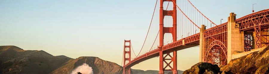 Golden Gate Bridge at sunrise viewed from the rocky coastline of San Francisco.