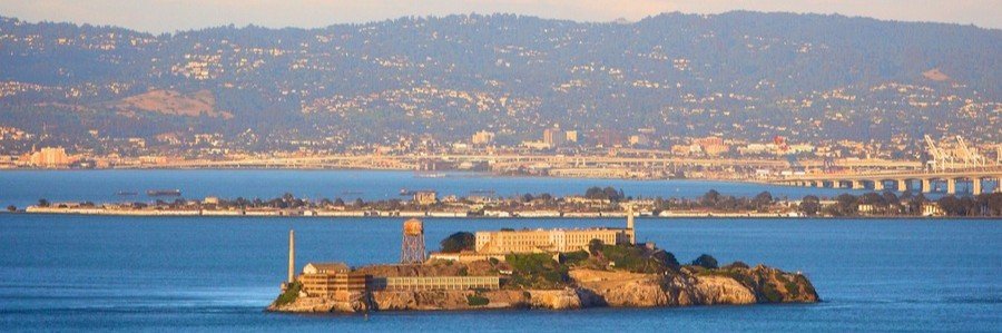 Alcatraz Island in San Francisco Bay with the historic prison and city skyline in the background.