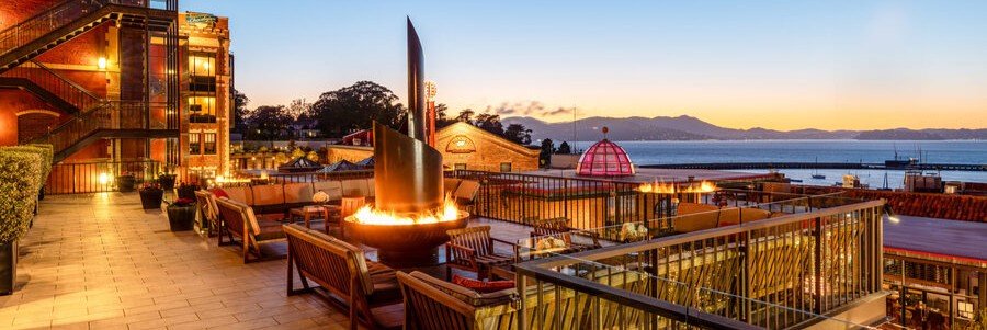 Outdoor terrace at Fairmont Heritage Place overlooking Ghirardelli Square and San Francisco Bay at sunset.