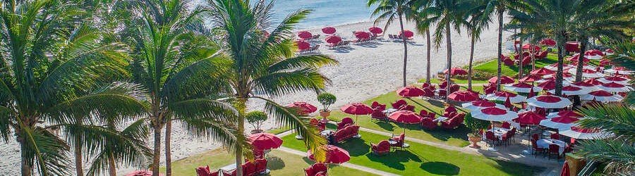 Iconic red umbrellas and crimson lounge chairs on the oceanfront lawn at Acqualina Resort and Residences On The Beach