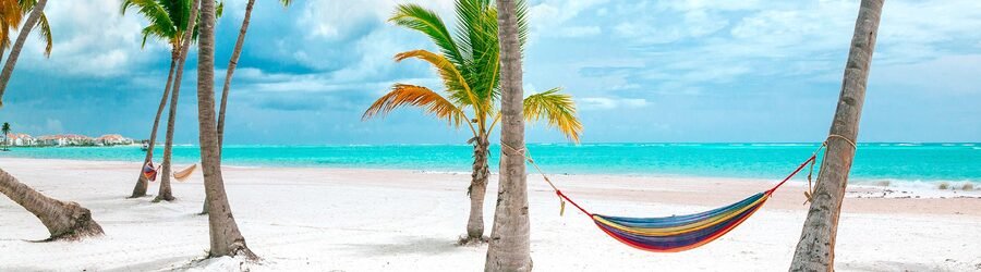 hammock between palm trees on a white sand Caribbean beach with turquoise water