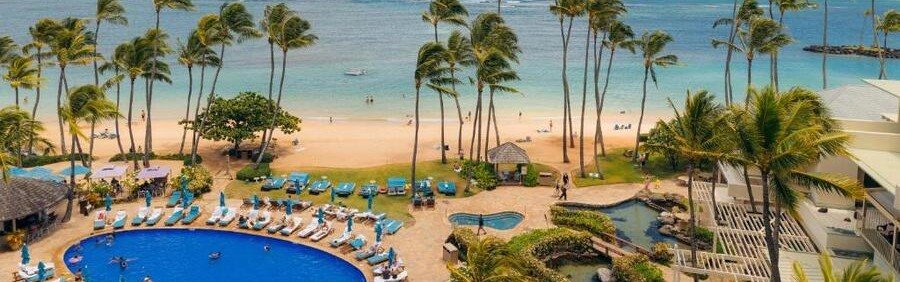 Aerial view of the circular swimming pool and palm-fringed sandy beach at The Kahala Hotel and Resort