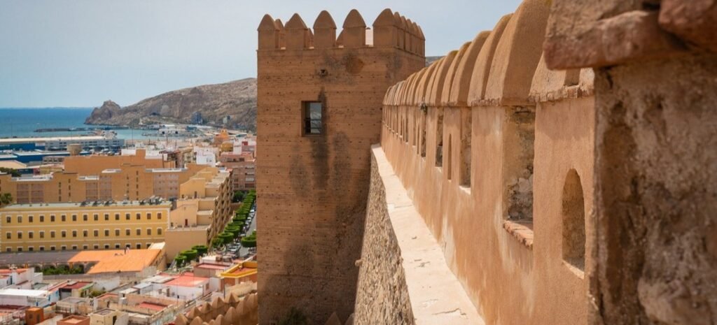 Views from the Historic Alcazaba of Almería | Beach Travel Destinations Ancient stone walls of the Alcazaba overlooking the city and Mediterranean coastline in Almería, Spain.