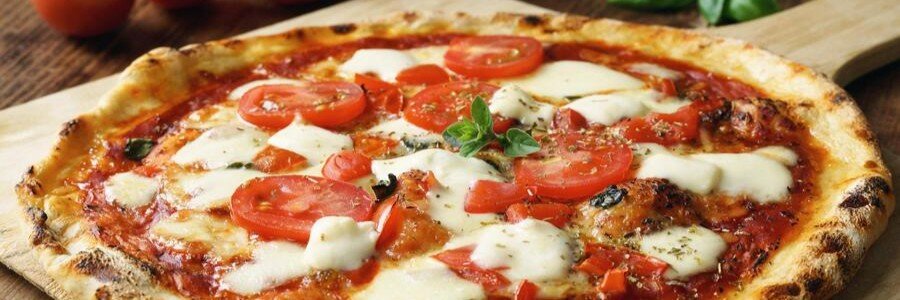 A close-up shot of a freshly baked, thin-crust Italian Margherita pizza topped with melted fresh mozzarella cheese, sliced tomatoes, tomato sauce, and oregano on a wooden serving board.