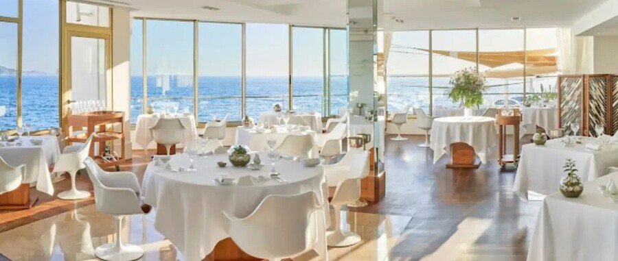 Elegant seaside dining room at Le Petit Nice Passedat in Marseille with ocean views and fine dining tables.