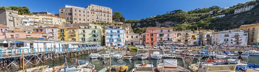 Small fishing boats and colorful buildings lining Marina Grande harbor in Sorrento, Italy