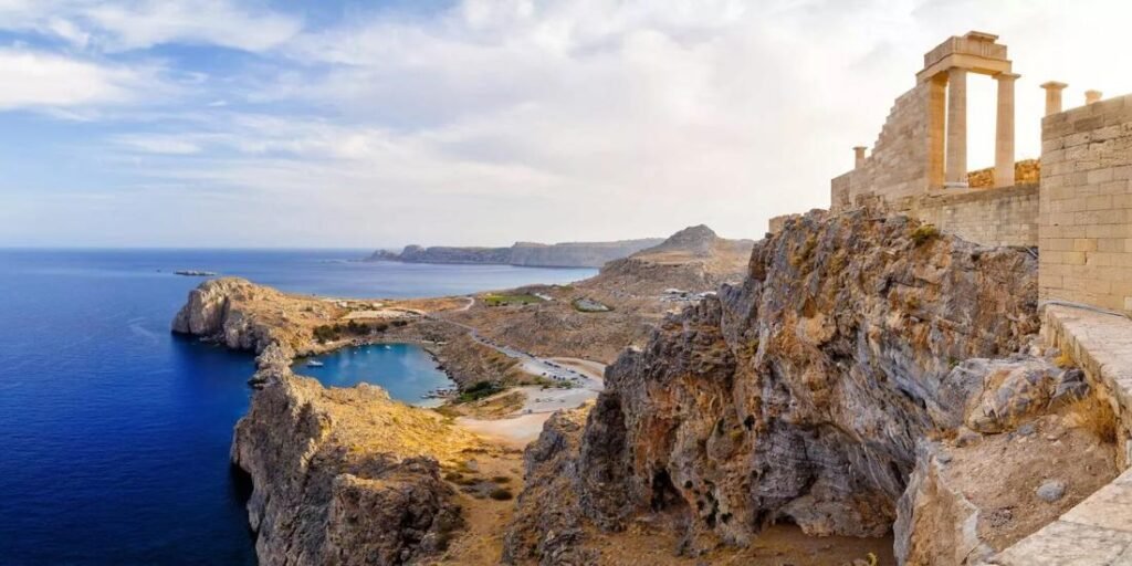 View of the Acropolis of Lindos in beautiful Rhodes, Greece, with whitewashed houses below and the Aegean Sea in the background.