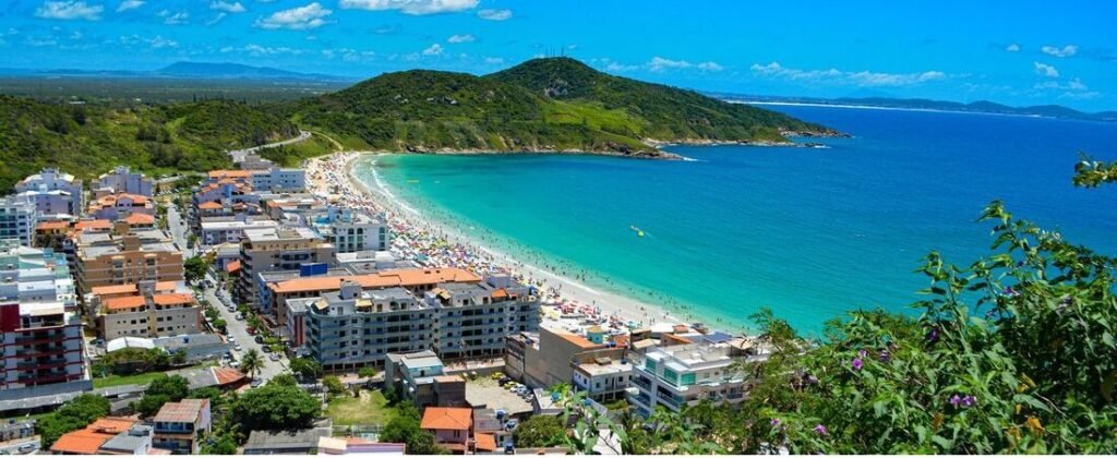 High angle panorama of Praia Grande beachfront town and vibrant turquoise ocean bay in Arraial do Cabo Brazil