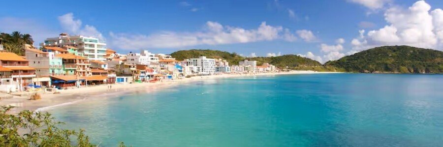 Clear turquoise bay and beachfront buildings along Prainha Beach in Arraial do Cabo.