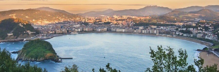 Panoramic view of La Concha Bay in San Sebastián at sunset with city and mountains
