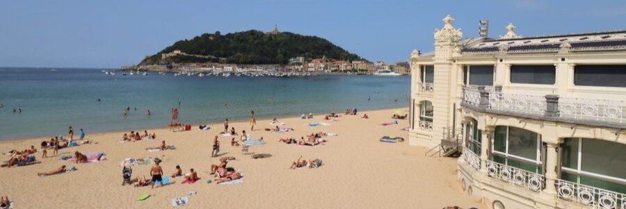 La Concha Beach in San Sebastián with golden sand, clear water, and historic seaside buildings