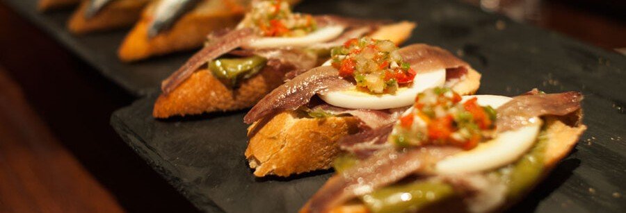 Traditional pintxos in San Sebastián with anchovies, eggs, and peppers on bread